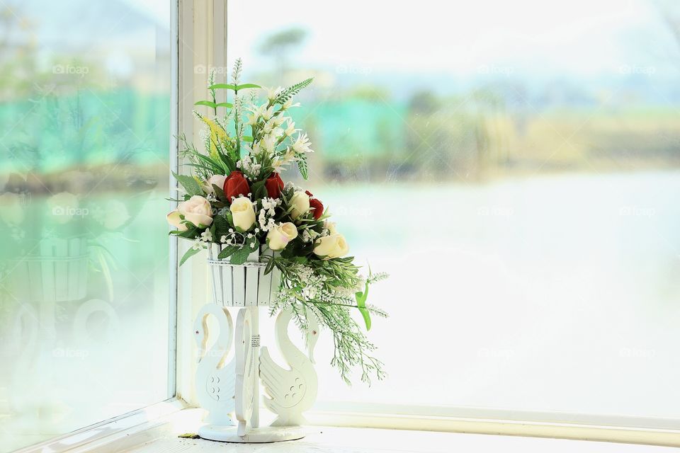 The flowers in the vase and near the glass windows.