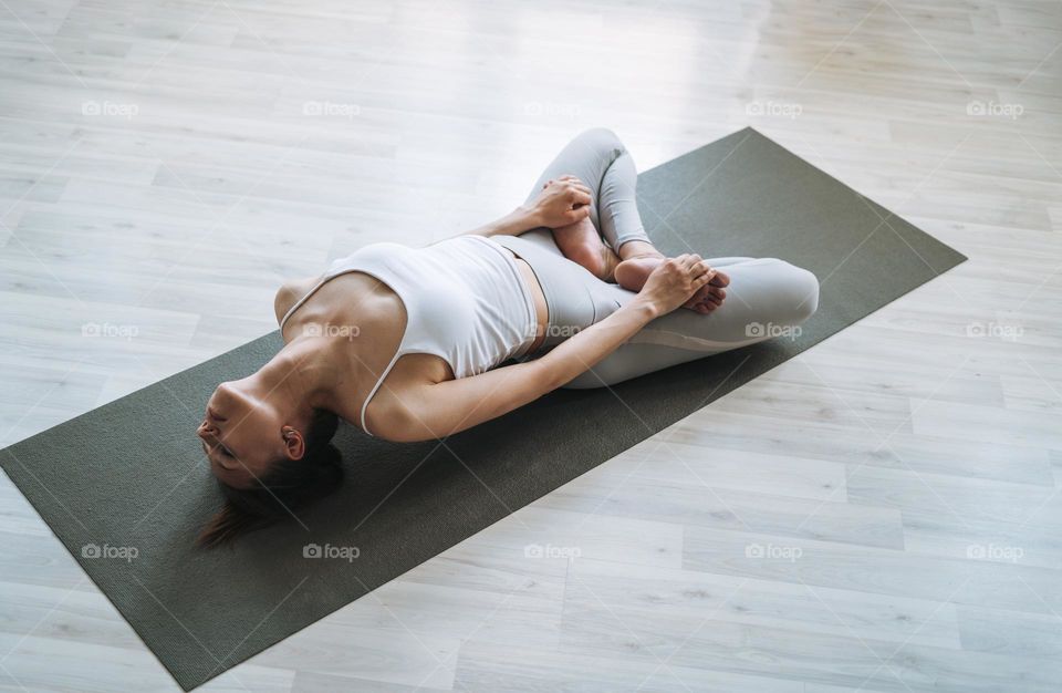 Young fit woman practice yoga doing asana in light yoga studio