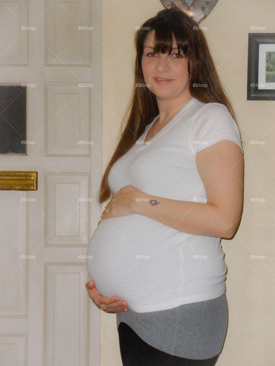 Third Trimester . Pregnant woman in the third trimester of her pregnancy, holding her baby bump, smiling. 