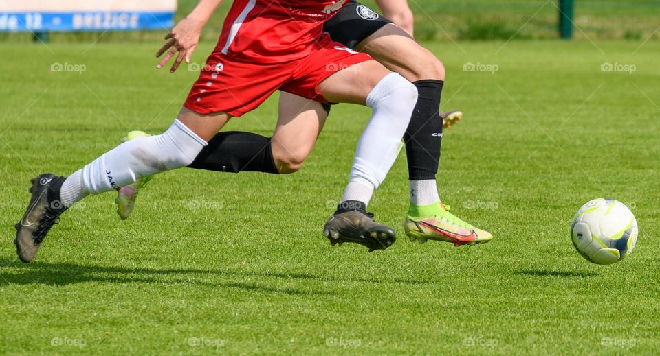 Low section of young football players chasing a ball during an official football match