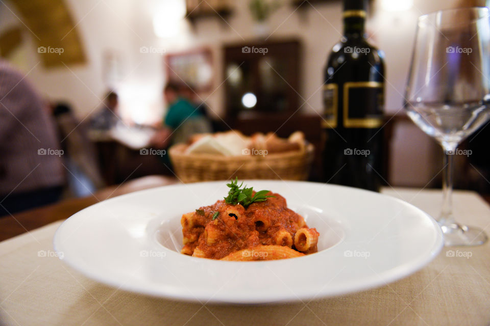 Pasta dish at the restaurant in Sicily with red wine and bread.