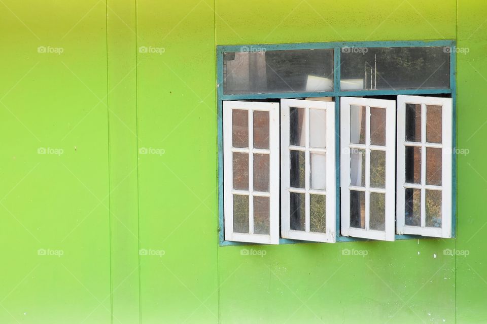 White wooden doors open in vintage style and dirty green plaster walls.