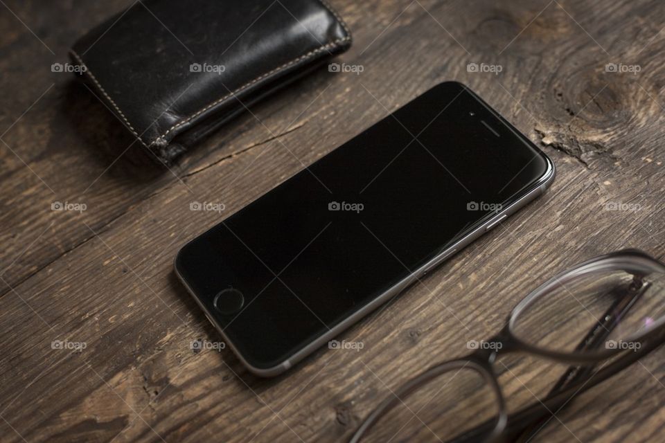 new iphone 6, glasses and wallet on wooden table, business items from a graphic designers pocket