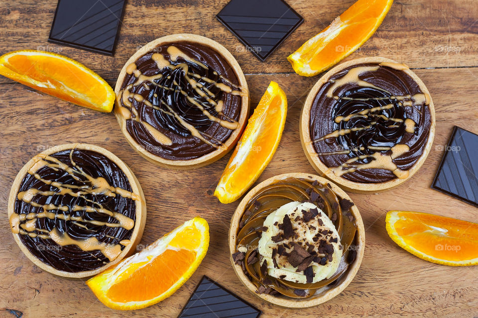 tartlets, peaces of chocolate and orange on the wooden table