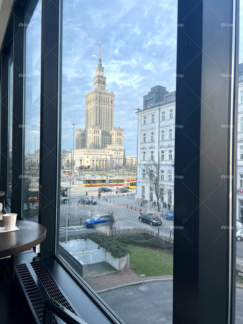 Из окна впечатляющий вид на Дворец Культуры и науки, символ Варшавы, возвышающийся над городом. Историческая архитектура, величественные контуры Сталинской эпохи 
