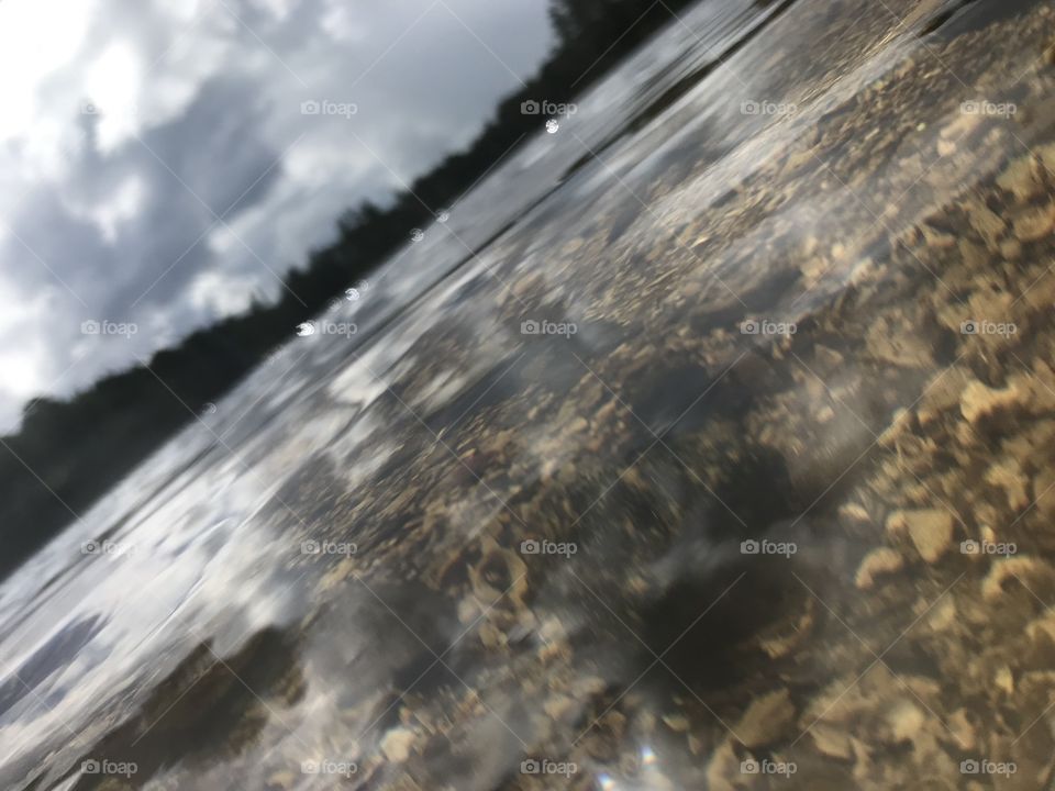 Picture taken right over the water in Norway. The landscape is very blurry and you can see a little bit in the water.