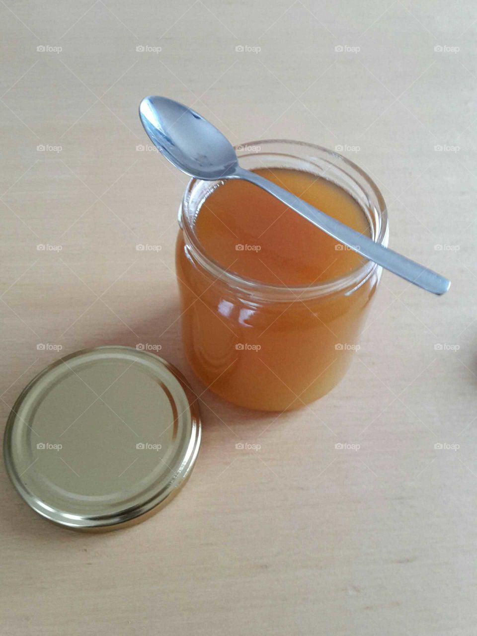 open glass of honey with a spoon