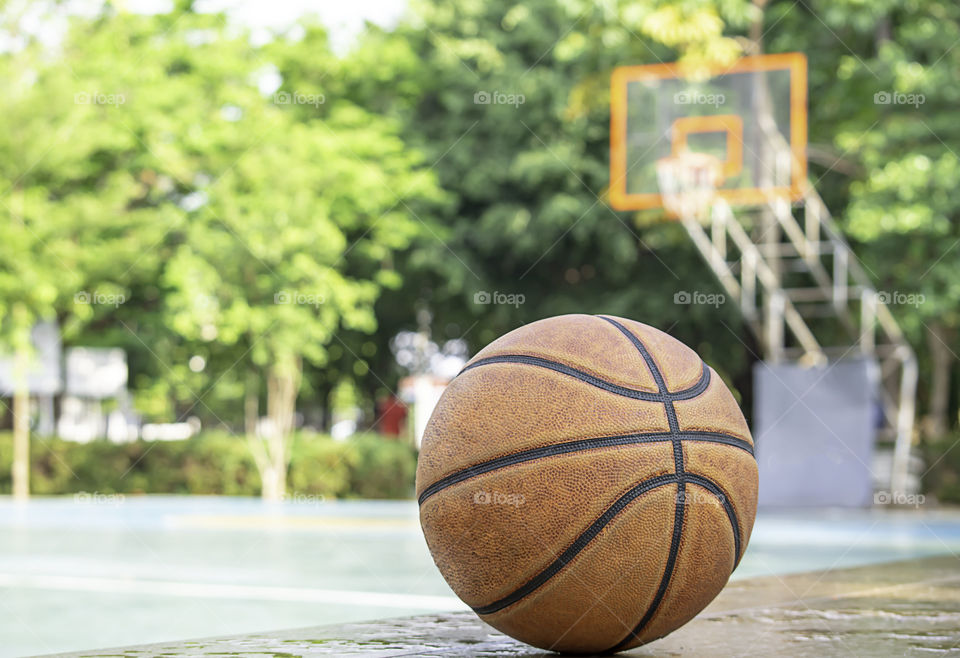 Basketball leather on the wooden chair with water droplets Background basketball court and park.