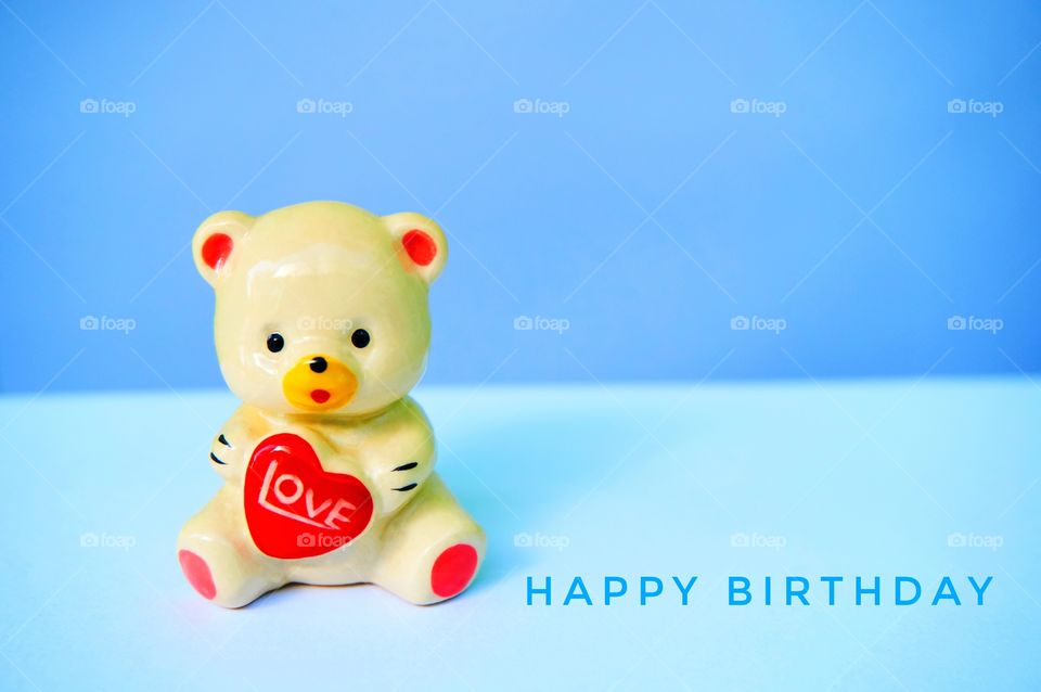 Teddy bear and happy birthday on blue background 