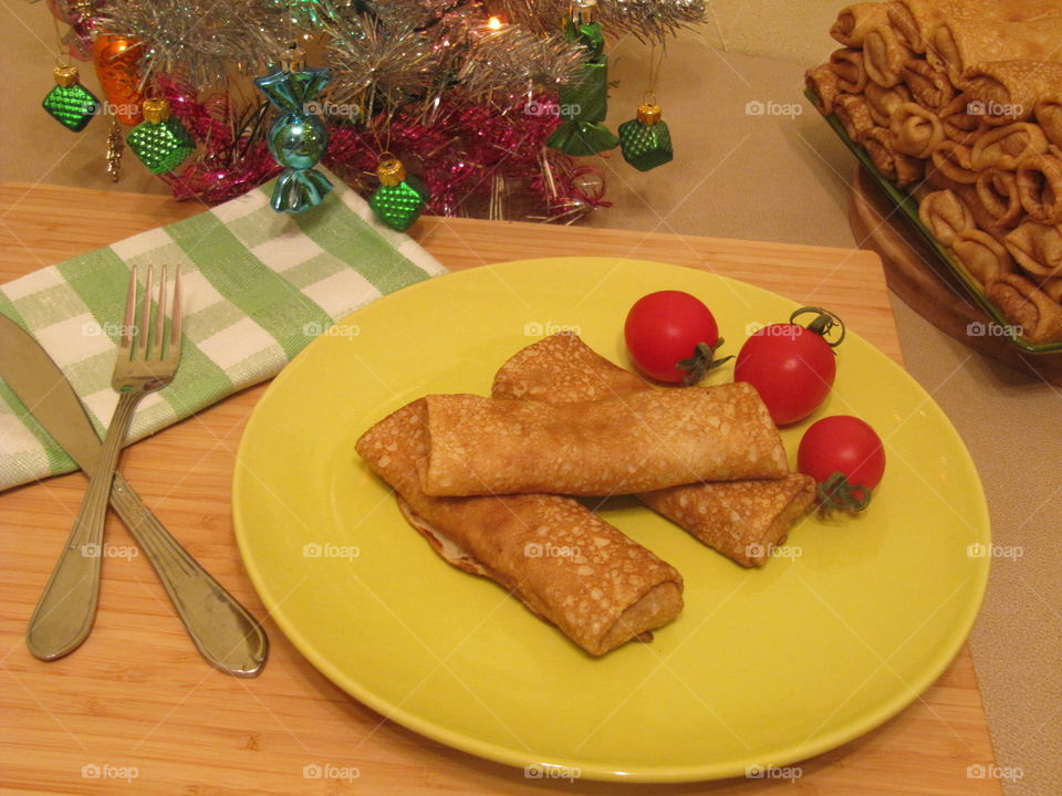 Crapes with meat and tomatoes and other vegetables in green plate on the wood
