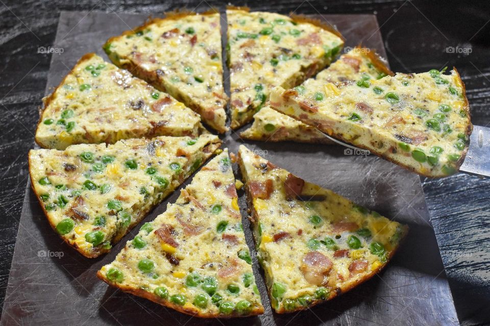 Homecooking cooking Frittata at home and adding and mixing ingredients and removing the Frittata from the pan for cutting and serving on a white plate with tomatoes. Healthy home cooking in kitchen. Breakfast and lunch food preparation.