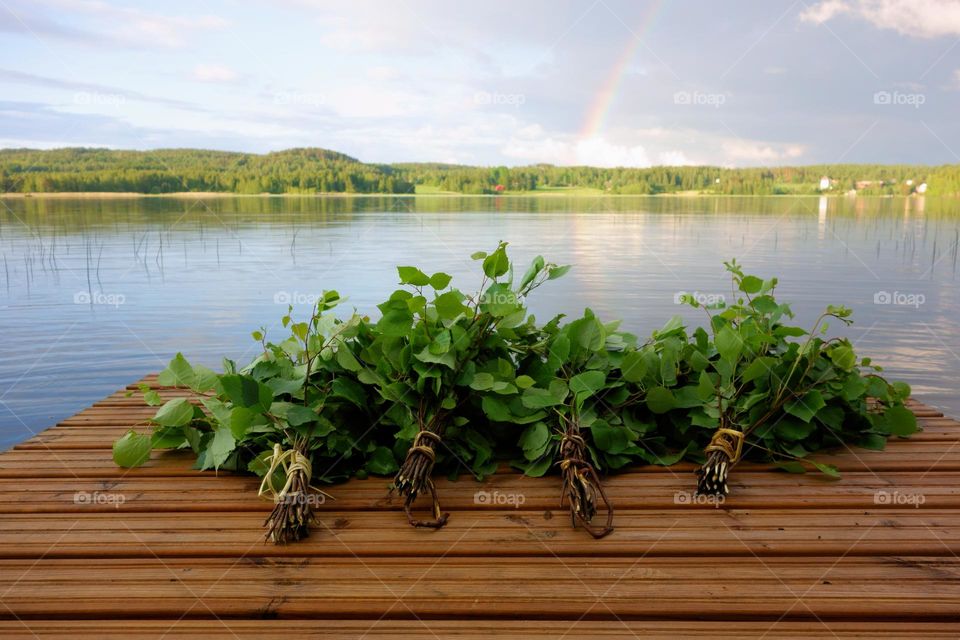 Traditional Finnish bath whisks made out of fresh birch leaves and twigs on a wet jetty by the lake on midsummer eve.