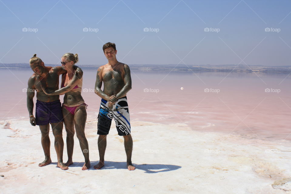 Friends standing at river bank with mud on their body