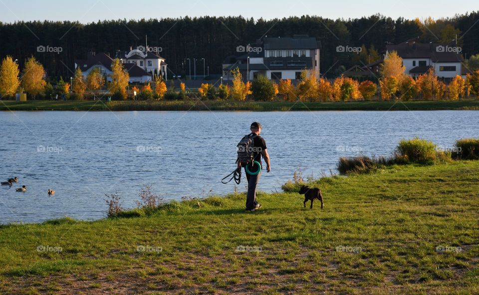 men walking with dog autumn beautiful landscape lake shore social distance