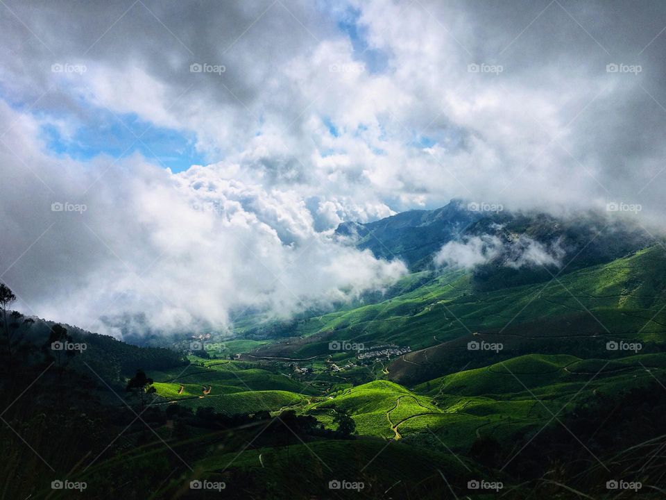 Serene view of clouds closing in on vast tea plantations in Munnar, India. 