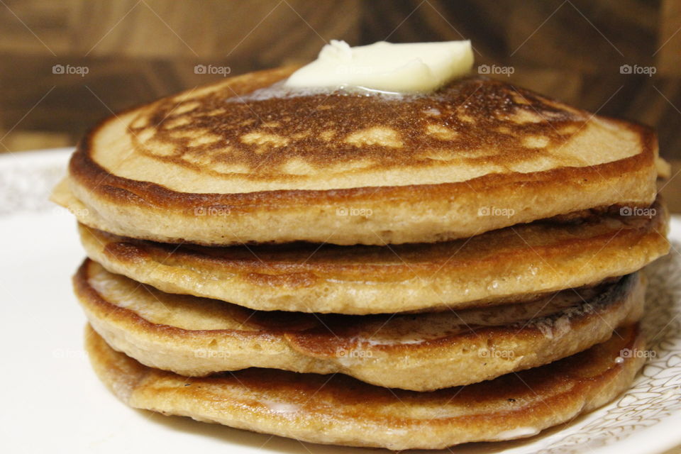 4 homemade pancakes stack high with melting butter on top