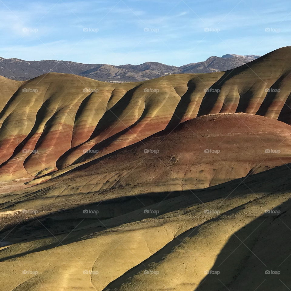 The incredible beauty of the red, gold, and browns of the textured Painted Hills in Eastern Oregon on a bright sunny day.