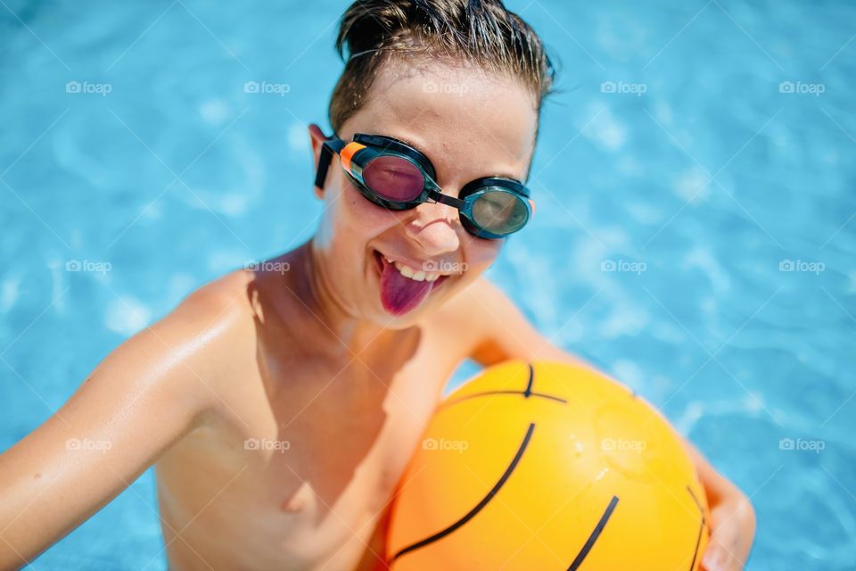 boy makes funny selfie in the pool