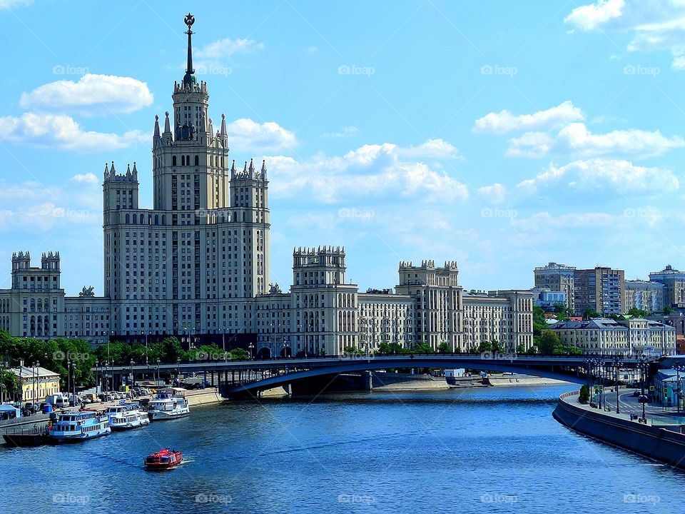 Summer in the city. Moscow river. Residential building on Kotelnicheskaya embankment. Small boats are moored at the pier of the river for excursions and walks on the water.