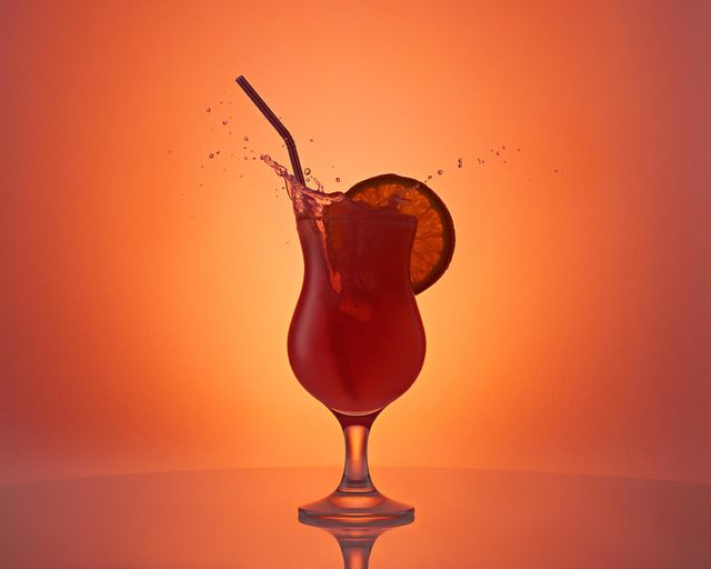 Cocktail with lemon and splashes on a red background