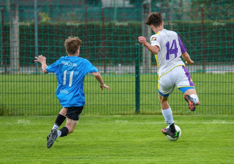 Rear view of two youth players playing an official football match