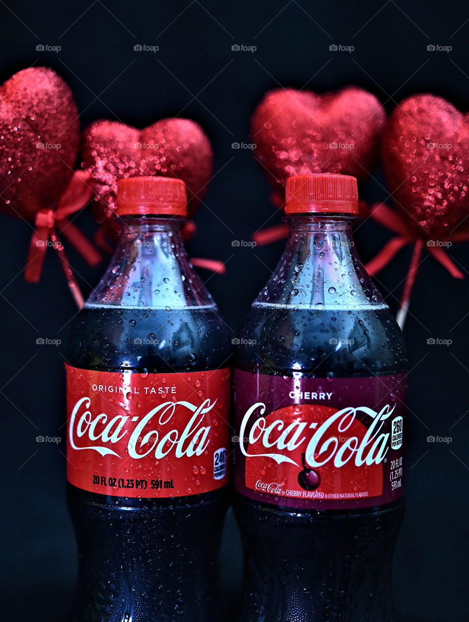 Close up shot of coke cola with valentine hearts in a black background in studio.
