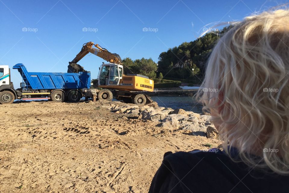 Boy watching digger on the beach