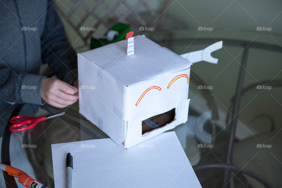 Young child crafting a cardboard robot indoors