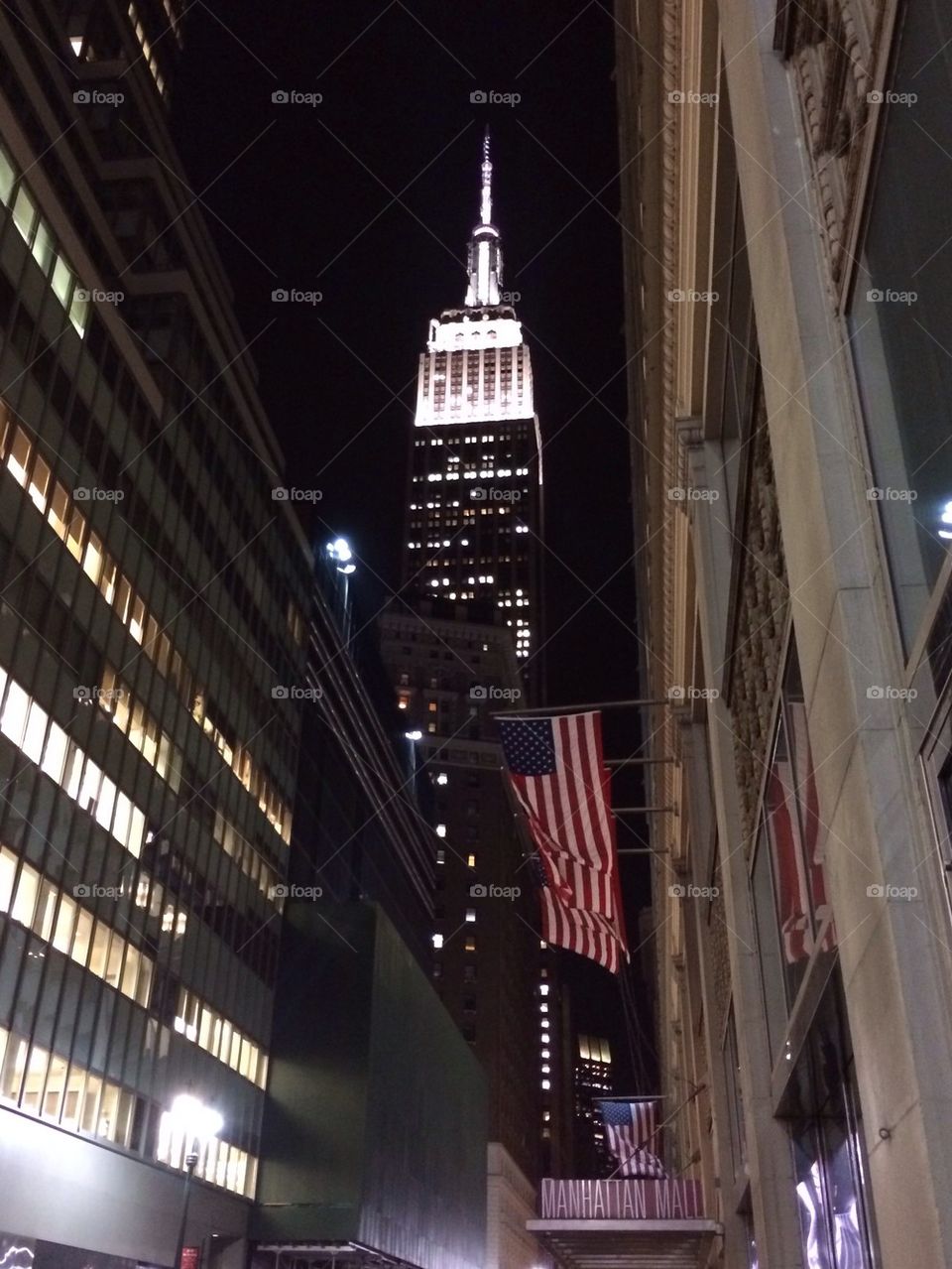 Empire State and American flags at night