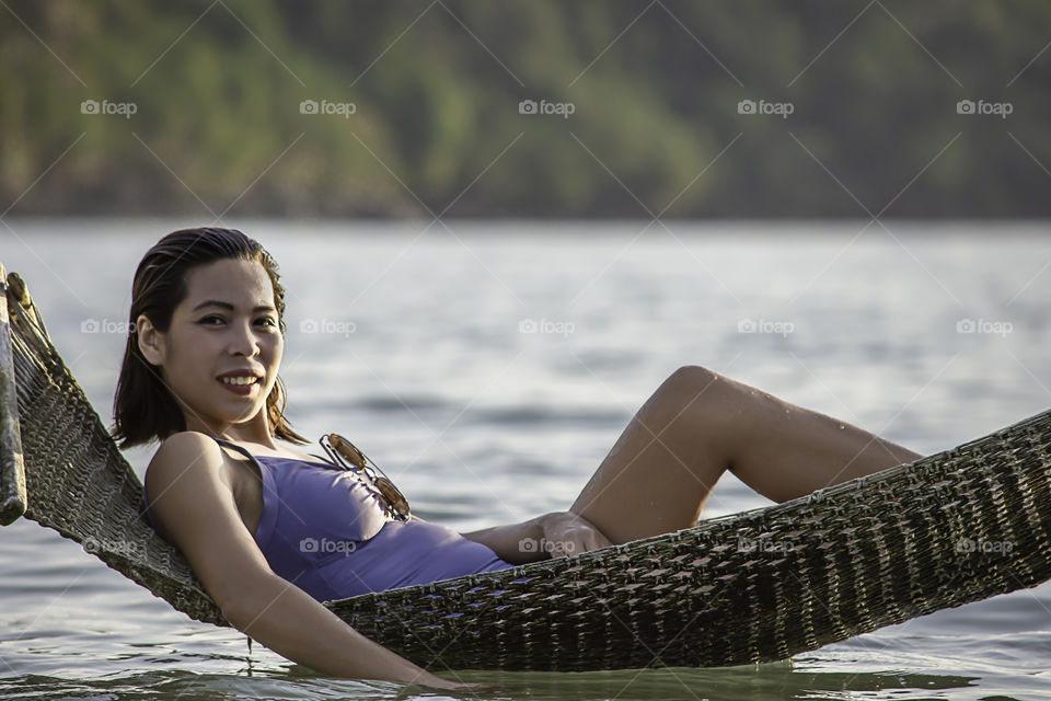 Portrait of Asian woman wearing a swimsuit on Hammock swing in sea.