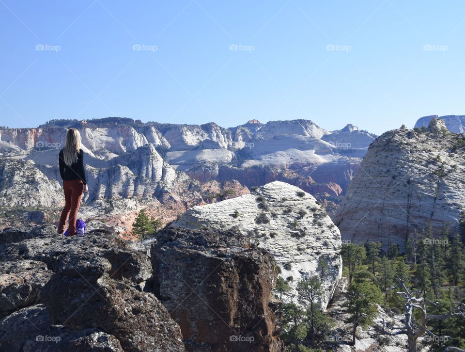 Blonde hiker girl taking in the views and vastness of Zion National Park. 