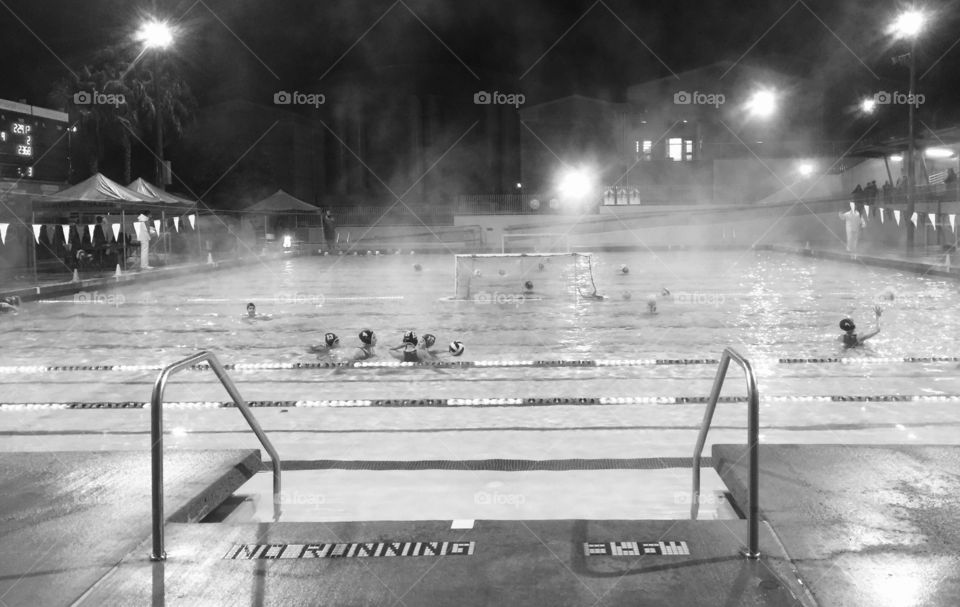 High school girls evening waterpolo game warmups in the rain and mist.  Winter sports. Girls are tough! 