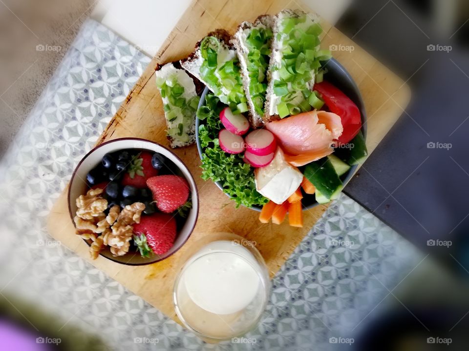 Wooden board with a salad bowl and oatmeal with a glass of buttermilk for breakfast