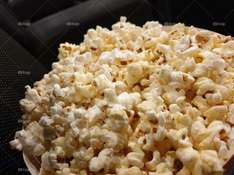 a close up portrait of a bucket of popcorn ideal to eat during a movie in a cinema theater.