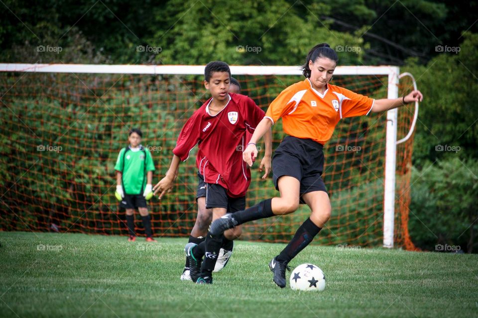 Teens are playing soccer outdoors