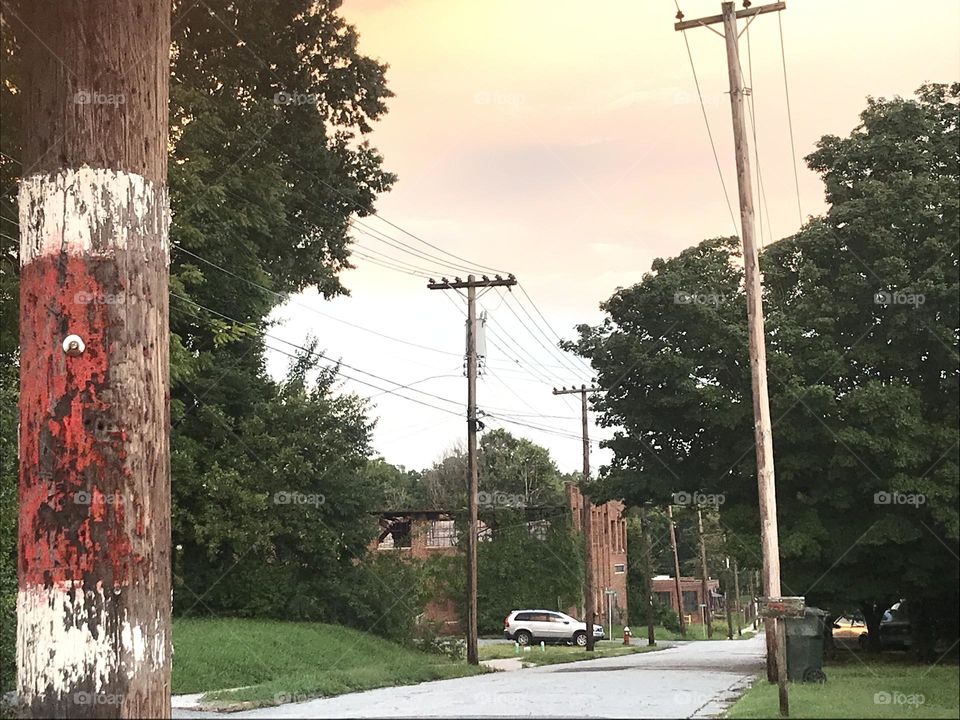 Photograph of a neighborhood street view, with burnt down abandoned warehouse in the distance. Taken in Thomasville, NC, USA.