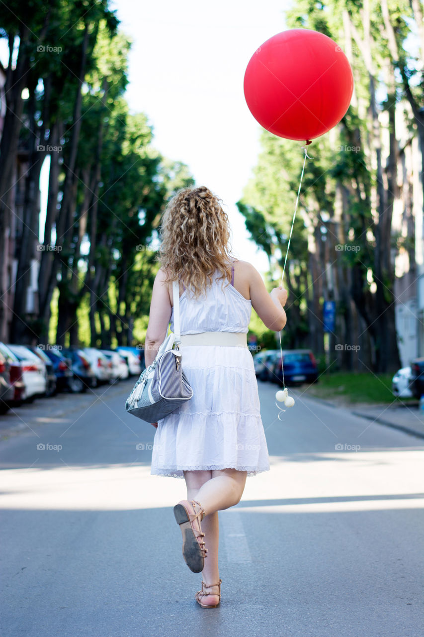 girl with red balloon. curly blond girl with big red balloon on the street