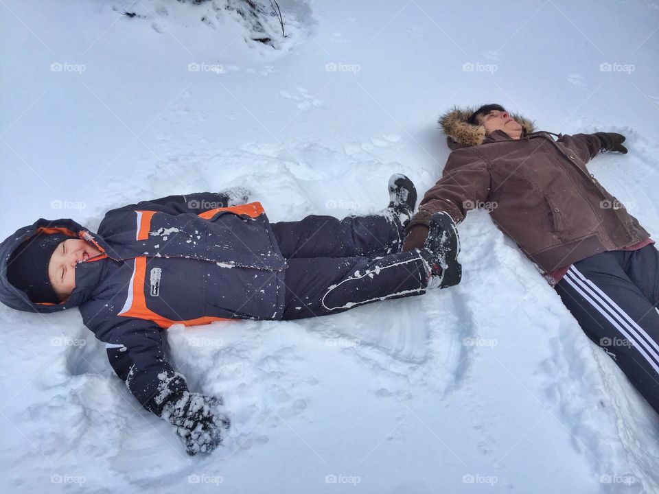 Father and son lying on snow in worm clothing