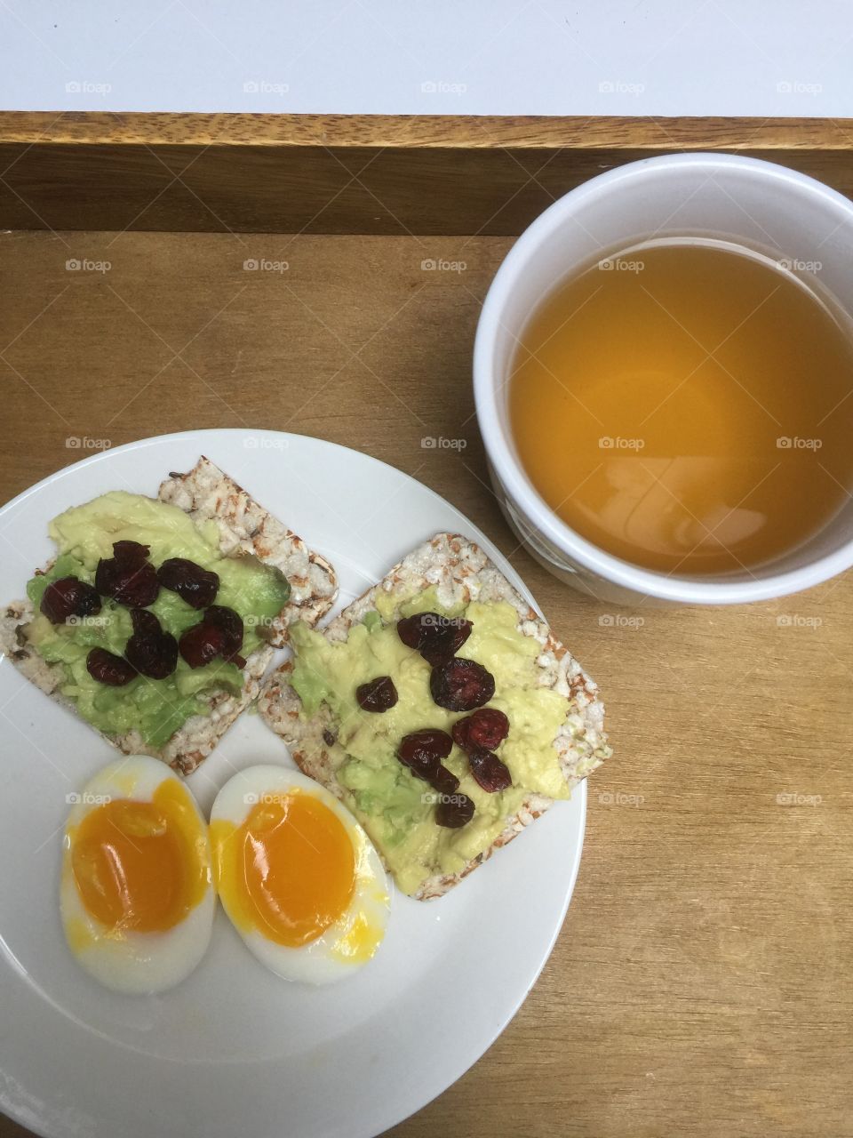 Healthy breakfast! Avocado and dried cranberries on thin rice cake with soft boiled egg and green tea