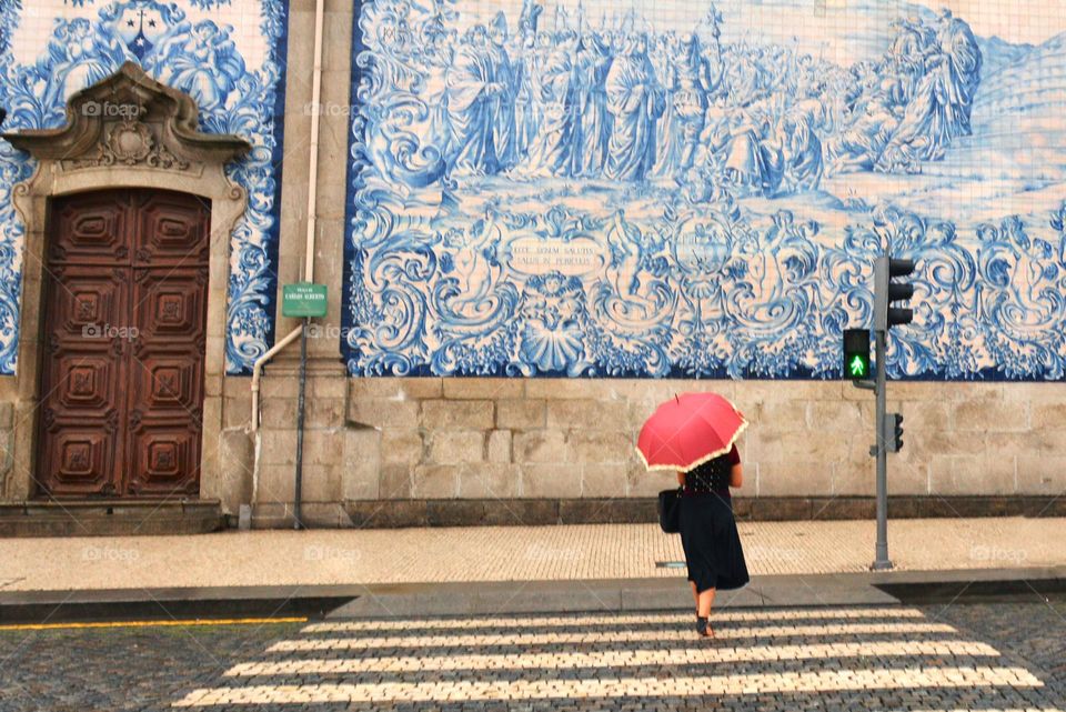 a girl with a red umbrella crosses the road