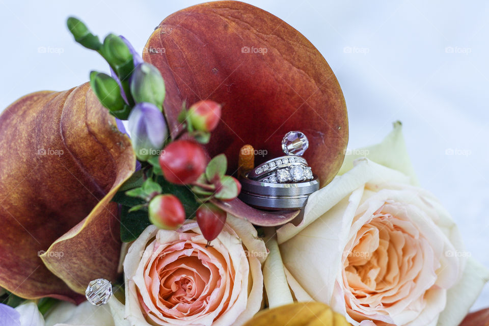 Bride and groom's wedding rings set inside a colourful wedding bouquet 