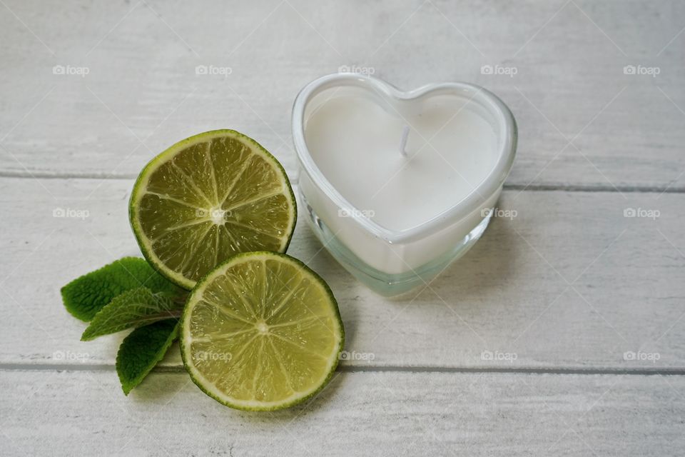 Heart shape candle on table with slices of lemon and mint