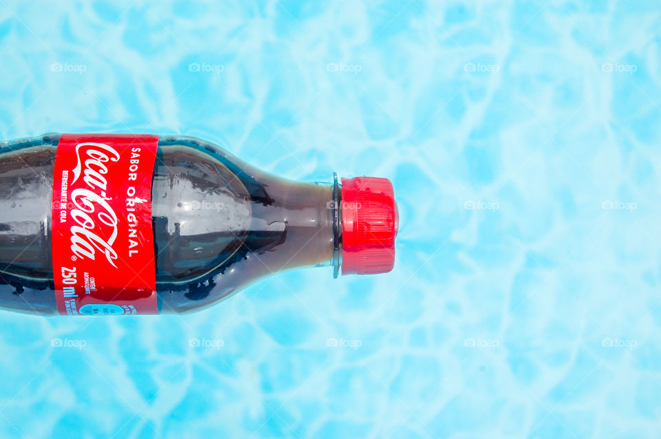 Coca Cola bottle in the swimming pool water