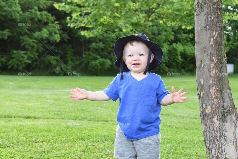 Cute happy toddler boy having fun exploring in nature park 