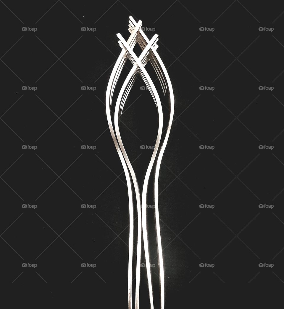 Close up four forks crossed isolated on black background. fork made from stainless steel