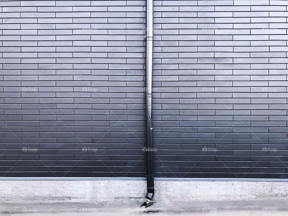 Metal pipe on metal brick wall background 