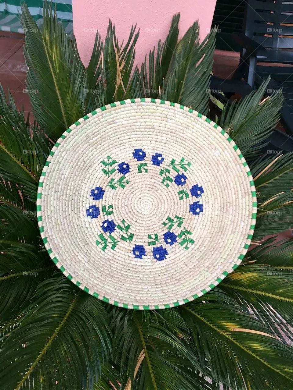 The image shows a group of hand -made dishes of wicker, decorated with colored embroideries with beautiful floral shapes, and is elegantly displayed in a warm corner that combines heritage and beauty, which gives the place an artistic spirit and attr