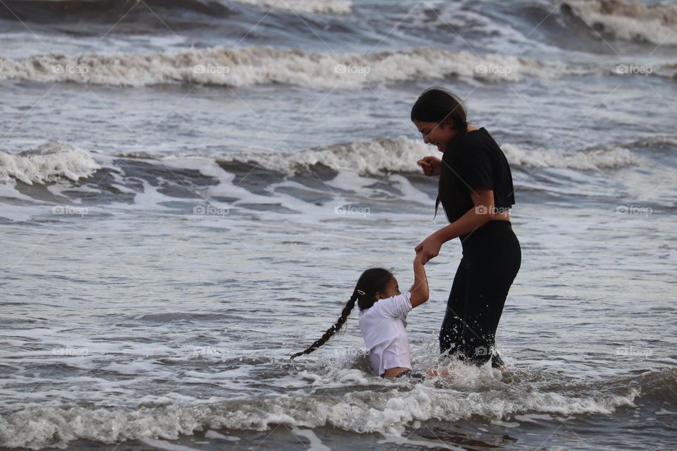 A young woman and a girl are playing in the waves of the Atlantic Ocean