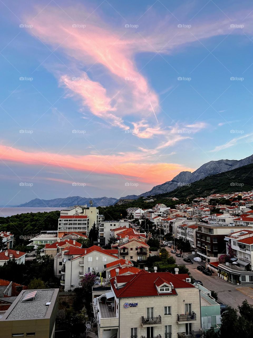 Beautiful tranquil sunset view with sun coloured clouds over the Mediterranean town red roof tops 