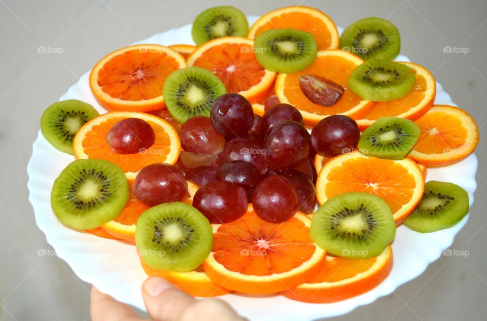 citrus and tropics fruits on a plate in the hand texture background